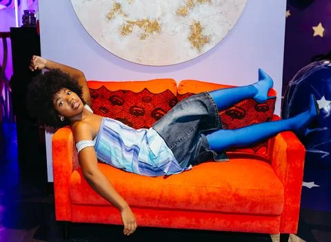 Creative Pose on a Bright Orange Couch Stock Photos