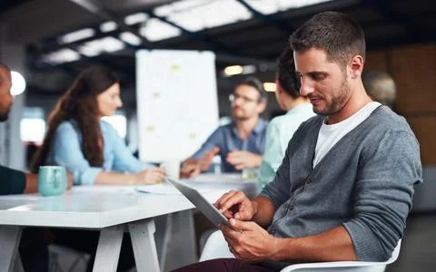 The creative process. a man sitting at a table in an office using a digital 写真素材