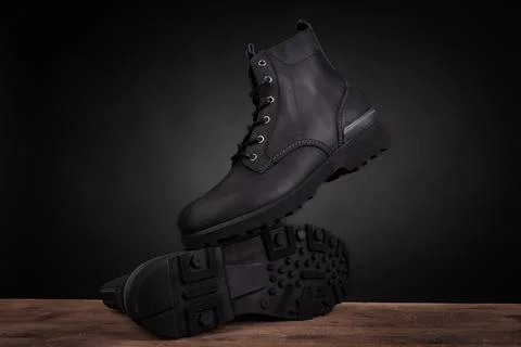 Creative product shot of men's black leather boots. Stylish and durable ank.. Stock Photos