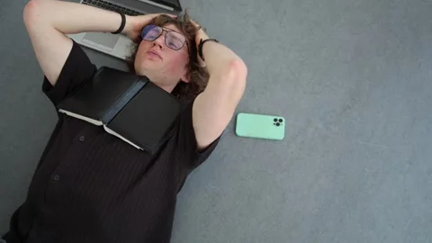 Creative professional lies on floor thinking through new ideas with notebook and Stock Footage 338277439