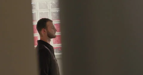 Creative profile shot of a young man seen through a door gap, standing in a room Video stock 347012137