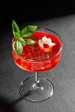 Creative red cocktail garnished with basil and fun ice shape in glass on da.. Stock Photos