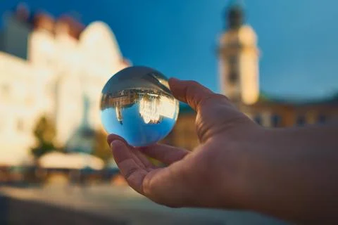 Creative refraction of historic town hall in glass lensball held by hand Stock Photos