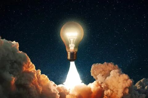 Creative rocket light bulb glows with smoke and blast successfully lift off.. Stock Photos
