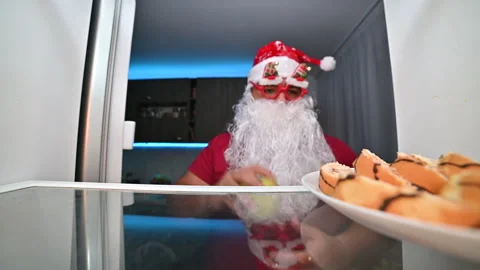 Creative Santa Claus open fridge and picking between cakes and healthy apple. Stock Footage 221782991
