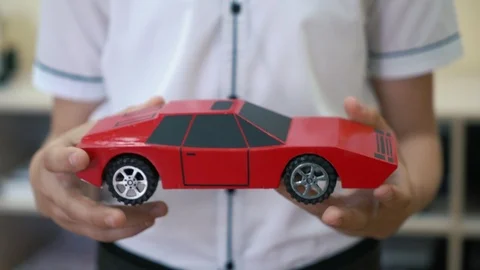 Creative schoolboy holding his handmade red cardboard car in the school. Close Видео 108440388