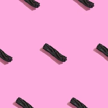 Creative seamless pattern with black liquorice candy on pink background. Swee Stock Photos