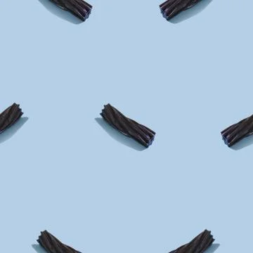 Creative seamless pattern with black liquorice candy on blue background. Swee Stock Photos