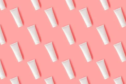 Creative seamless pattern from plastic cream tube on pastel pink background. Stock Photos