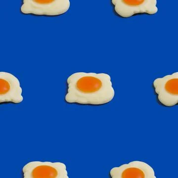 Creative seamless pattern with scrambled eggs on blue background. Food abstra Stock Photos