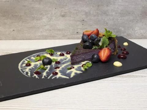 Creative serving of blueberry pie on slate and cream tree with mint leaves Stock Photos
