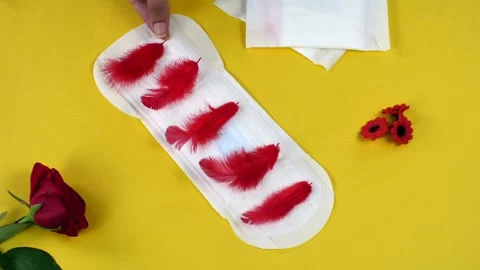 A creative shot of a sanitary pad with soft red feathers kept on a yellow bac... Stock-Footage 264025909
