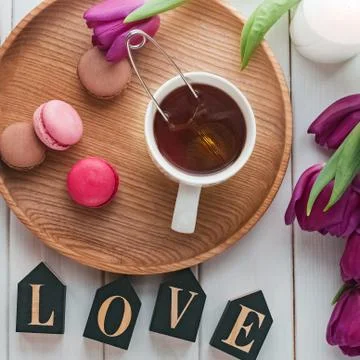 Creative spring composition with tea, macarons, purple tulipsand wooden letters Stock Photos
