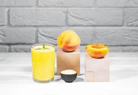 Creative still life with fruit smoothie, peach and maca on wooden podium Stock Photos