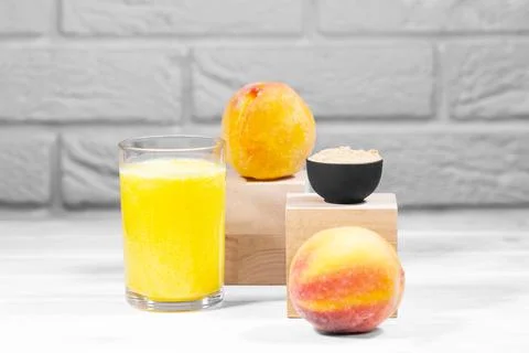 Creative still life with fruit smoothie, peach and maca on wooden podiums Stock Photos