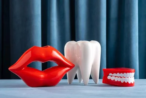 Creative still life with lips, teeth and jaw on blue velvet background. Den.. Stock Photos