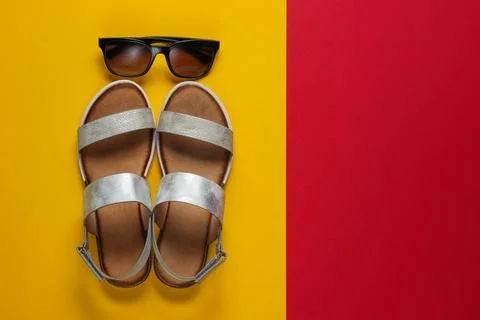 Creative summer beach flat lay. Leather women's sandals, sunglasses on yellow Stock Photos