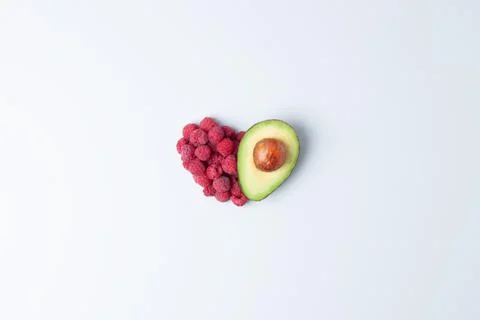 Creative summer concept. Heart shape made from fresh berries and avocado on g Stock Photos