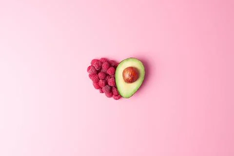 Creative summer concept. Heart shape made from fresh berries and avocado on p Stock Photos