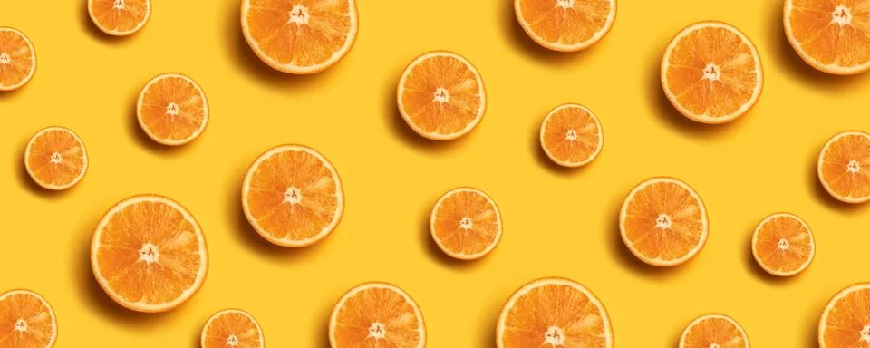 Creative summer pattern made of fresh orange slices on yellow background. Stock Photos