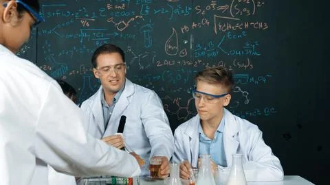 Creative teacher pointing at blackboard while talking to smart boy. Edification. Stock Photos