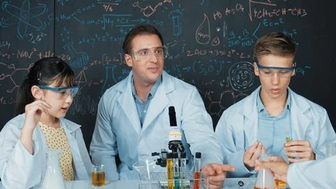 Creative teacher pointing at blackboard while talking to smart boy. Edification. Stock Photos