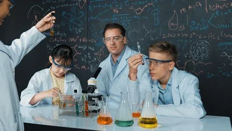 Creative teacher pointing at blackboard while talking to smart boy. Edification. Stock Photos