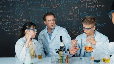 Creative teacher pointing at blackboard while talking to smart boy. Edification. Stock Photos