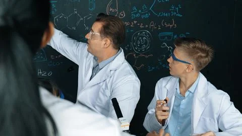 Creative teacher pointing at blackboard while talking to smart boy. Edification. Stock Photos