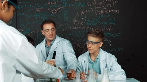 Creative teacher pointing at blackboard while talking to smart boy. Edification. Stock Photos
