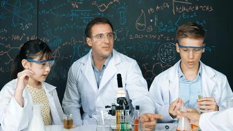 Creative teacher pointing at blackboard while talking to smart boy. Edification. Stock Photos