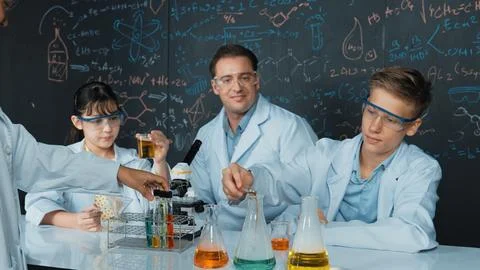 Creative teacher pointing at blackboard while talking to smart boy. Edification. Stock Photos