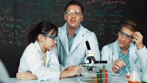 Creative teacher pointing at blackboard while talking to smart boy. Edification. Stock Photos