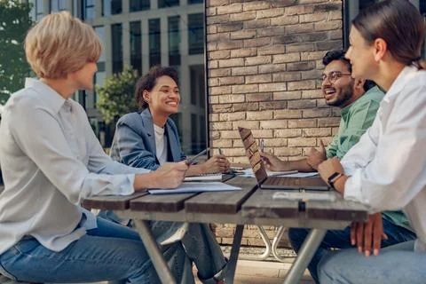 Creative team collaborating on project during meeting in outdoor cafe Stock Photos