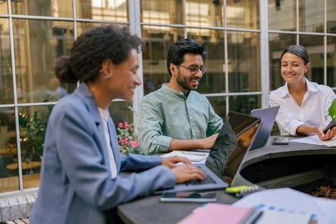 Creative team collaborating on project during meeting in outdoor cafe Stock Photos