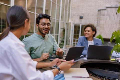 Creative team collaborating on project during meeting in outdoor cafe Stock Photos