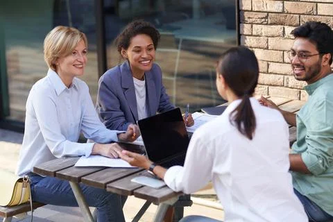 Creative team collaborating on project during meeting in outdoor cafe Stock Photos