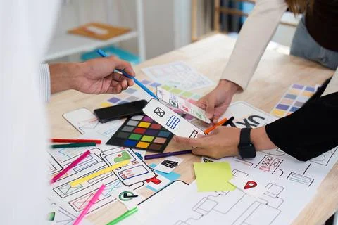 Creative Team Collaborating on UX UI Design with Colorful Prototypes and Stock Photos