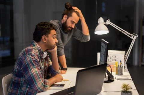 Creative team with computer working late at office Stock Photos