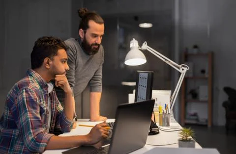 Creative team with computer working late at office Stock Photos