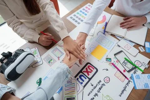 Creative tech team stacking hands over UX UI design sketches and VR headset Stock Photos