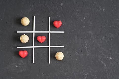 Creative tic-tac-toe game with red heart shapes and small round candies Foto stock