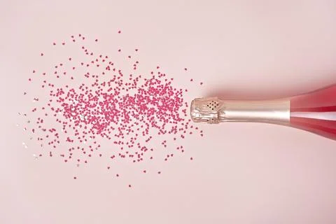 Creative trendy flat lay with pink heart shaped confetti poured out of champagne Stock Photos