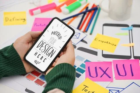 Creative UX UI designer hand holding mobile white screen mockup at working de Stock Photos