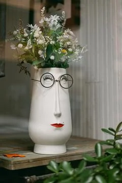 Creative vase designed as a human face with flowers displayed in a shop window Foto stock