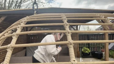 Creative view of a person cleaning a patio through a garden swing frame Vídeos de archivo 333075345