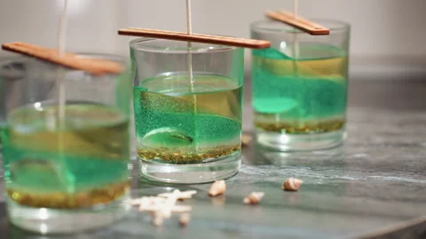 Creative Woman Drops Decorative Shell Beside Candle Jars on Kitchen Countertop Stock Footage 307991532