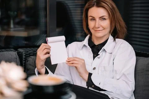 Creative woman engaging in note-taking during coffee break at modern cafe Stock Photos