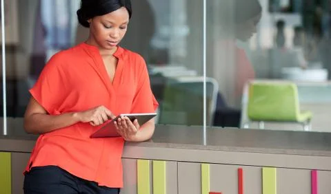 Creative woman using digital tablet while leaning against colourful cabinet Stock Photos