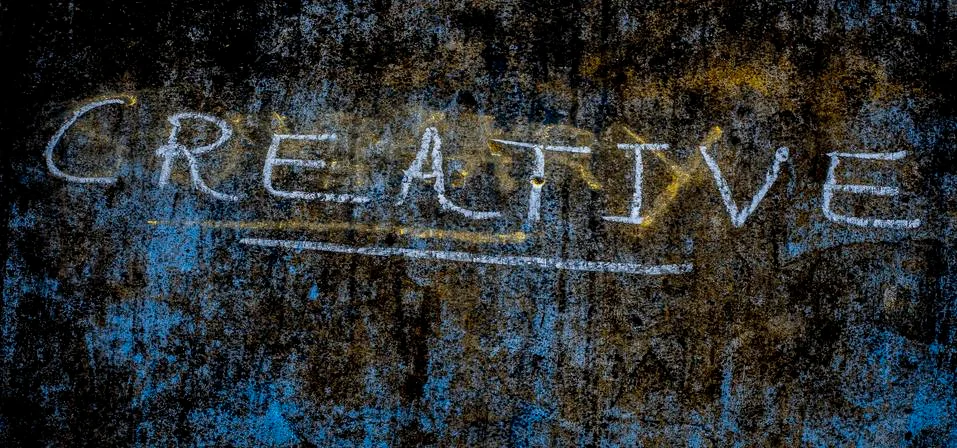 The creative word is written on a rough wall, close up shot, horizontal orien Stock Photos